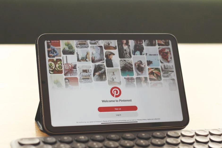 Un espace de travail soigné présentant un bloc à croquis avec des wireframes, un smartphone et un clavier sur un bureau en bois.